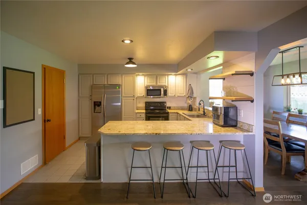 a kitchen with stainless steel appliances granite countertop table chairs refrigerator and sink