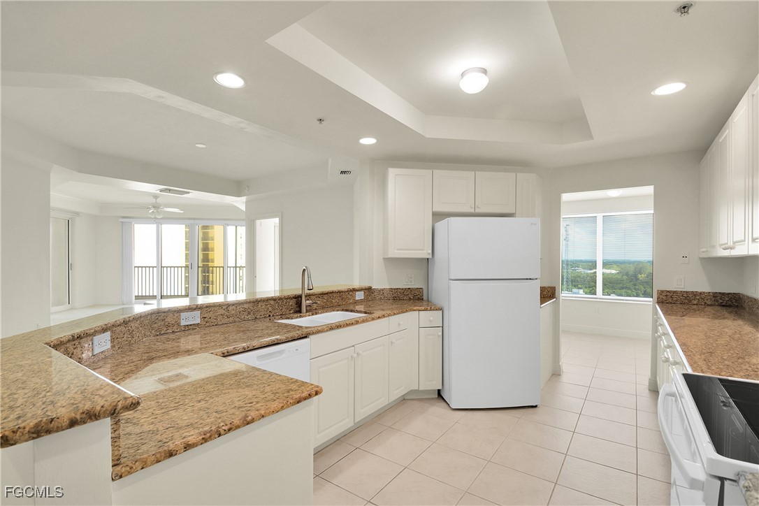 2743 First Street, Unit 1006 Fort Myers, FL 33916 - Photo 13 of 38 a kitchen with a stove a refrigerator and white cabinets with wooden floor