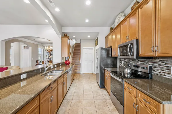 a large kitchen with stainless steel appliances granite countertop a sink and cabinets