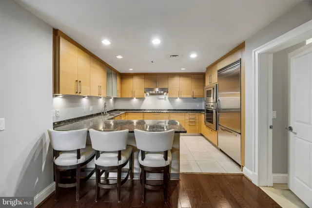 a kitchen with stainless steel appliances granite countertop a sink a stove a dining table and chairs