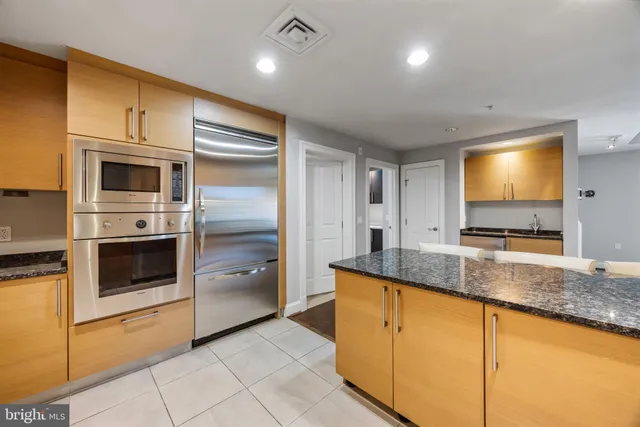 a kitchen with stainless steel appliances granite countertop a sink and a refrigerator