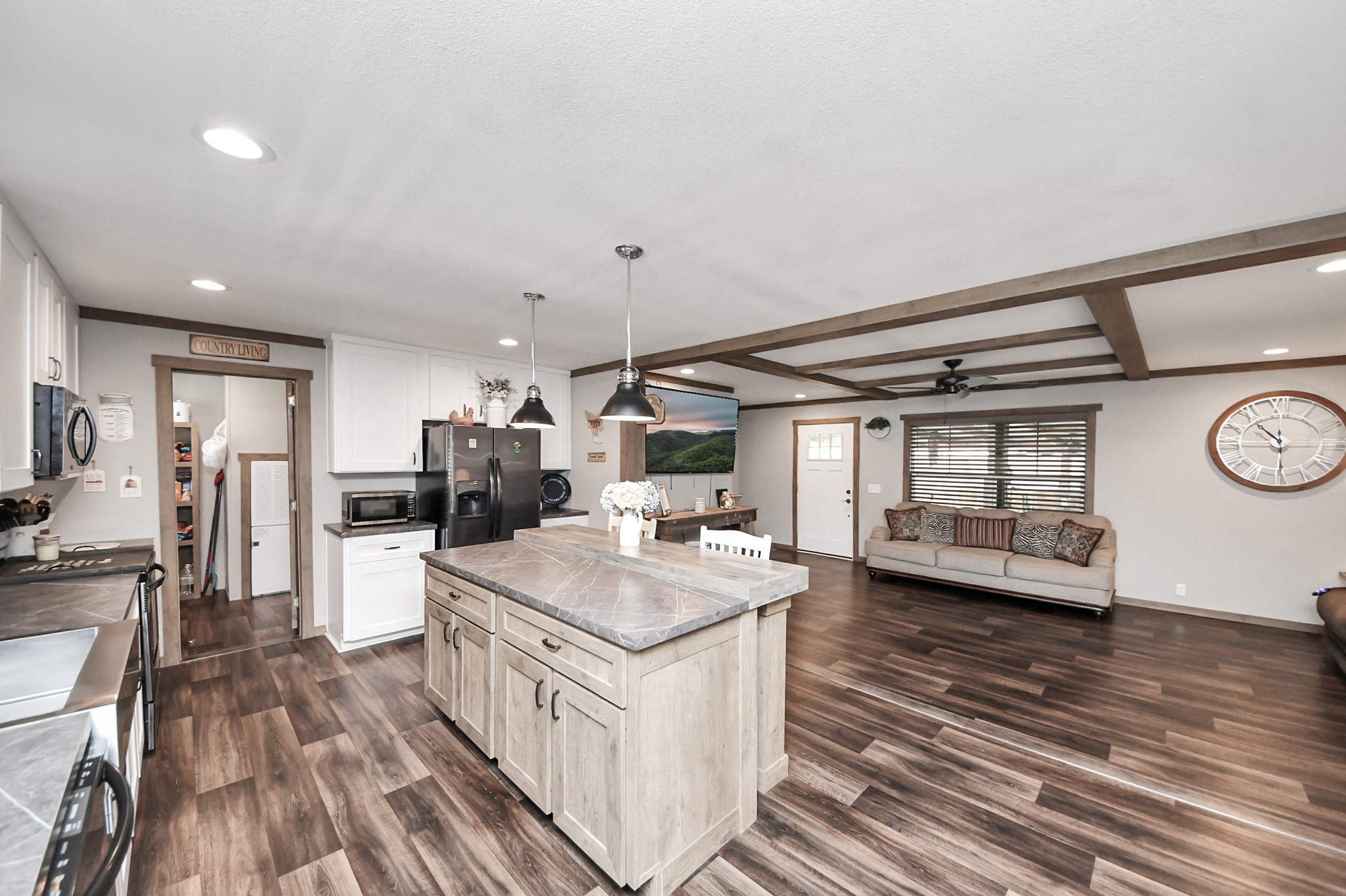 131 Kiowa Court Rosharon, TX 77583 - Photo 6 of 42 This open-concept space flows into a cozy living area with wood-beamed ceilings and large windows, creating a welcoming atmosphere perfect for entertaining.