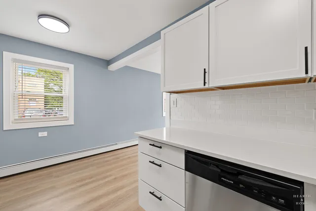 a kitchen with granite countertop white cabinets and wooden floor