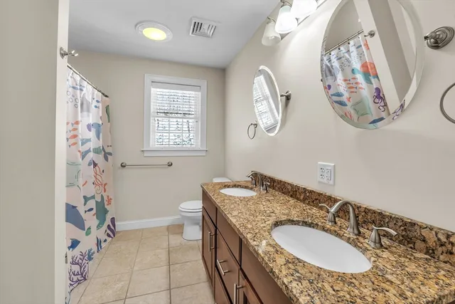 a bathroom with a granite countertop sink mirror vanity and toilet