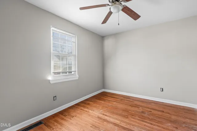 an empty room with a window and a ceiling fan