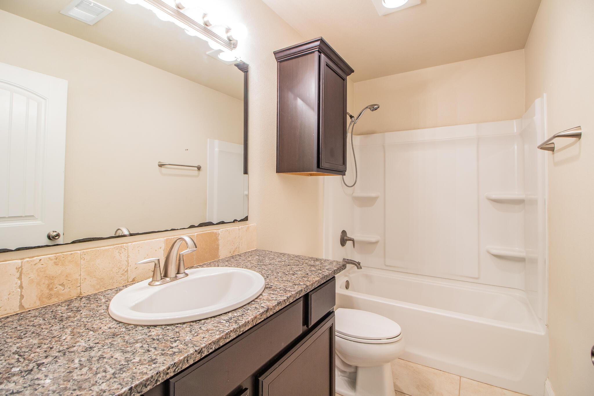 7409 101st Street Lubbock, TX 79424 - Photo 17 of 22 a bathroom with a granite countertop sink toilet and shower
