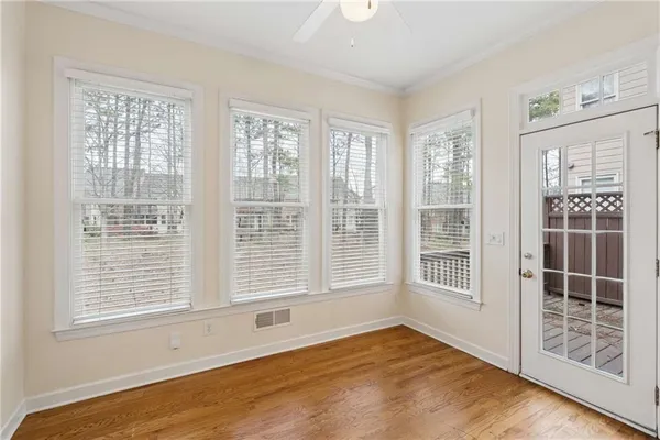 a view of an empty room with wooden floor and windows