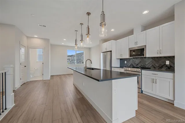 a large kitchen with granite countertop a large counter top stainless steel appliances and wooden floor