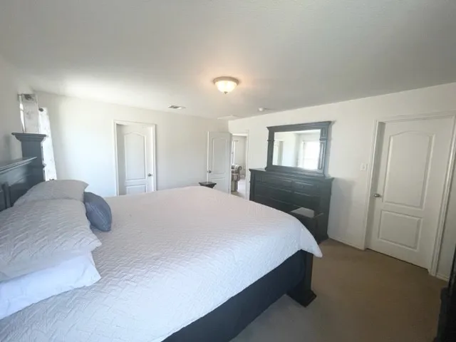 a spacious bedroom with a bed and a lamp