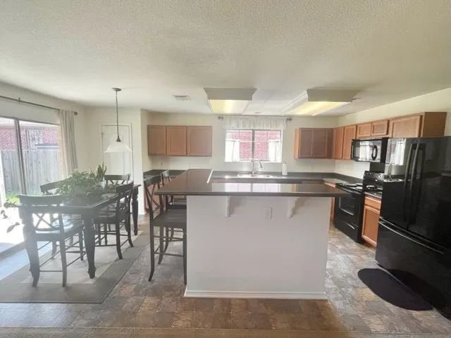 a kitchen with stainless steel appliances kitchen island granite countertop a stove a sink a refrigerator and a dining table