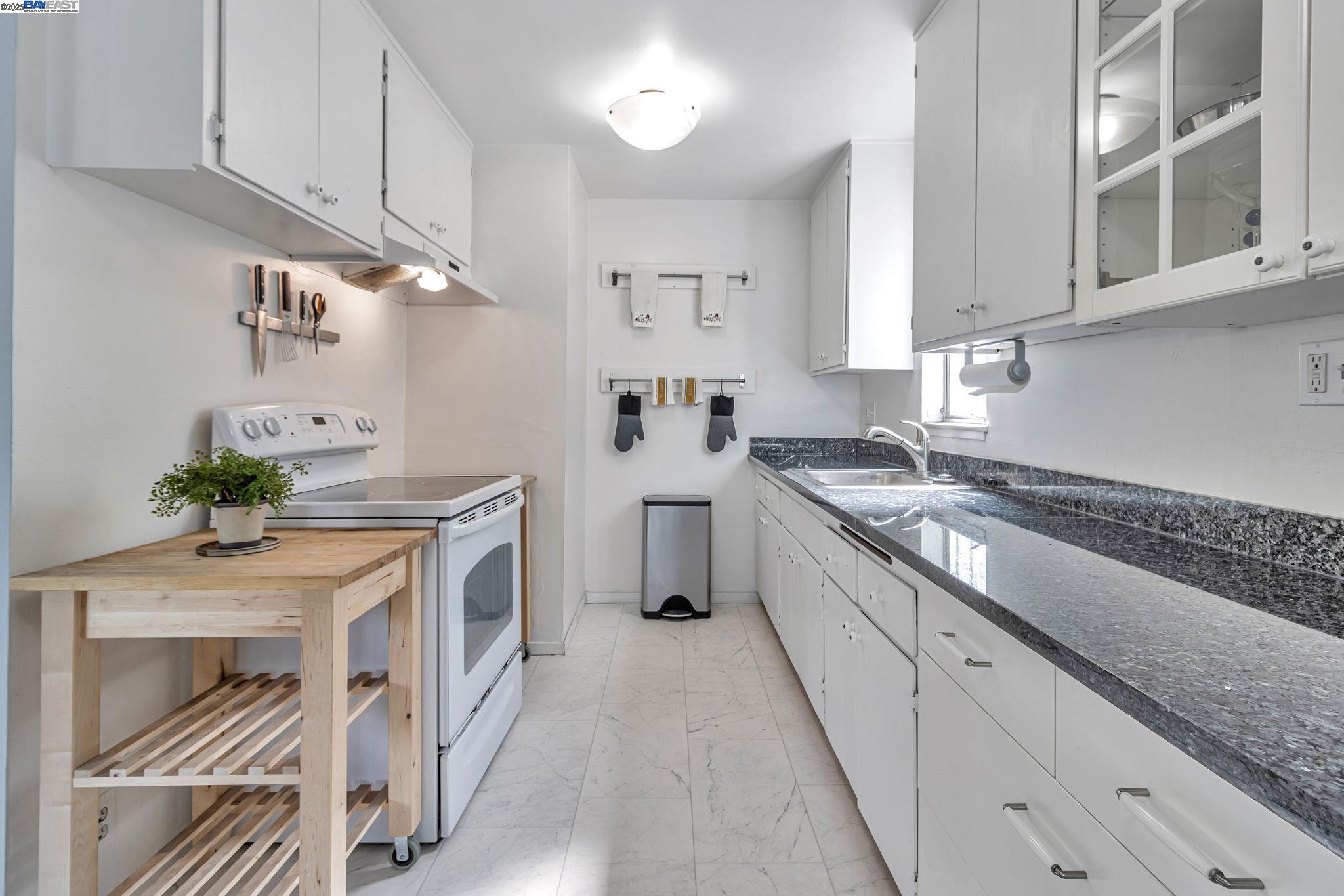 3877 Howe Street, Unit 106 Oakland, CA 94611 - Photo 5 of 17 a kitchen with stainless steel appliances granite countertop a stove a sink and a white cabinets