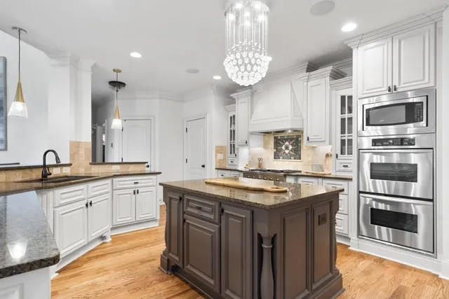 a bedroom with a large bed a flat tv screen and a chandelier
