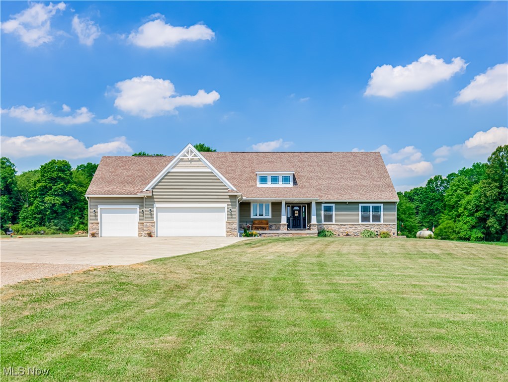 961 Industry Road Atwater, OH 44201 - Photo 1 of 50 View of front facade featuring stone siding, concrete driveway, an attached garage, and a front lawn