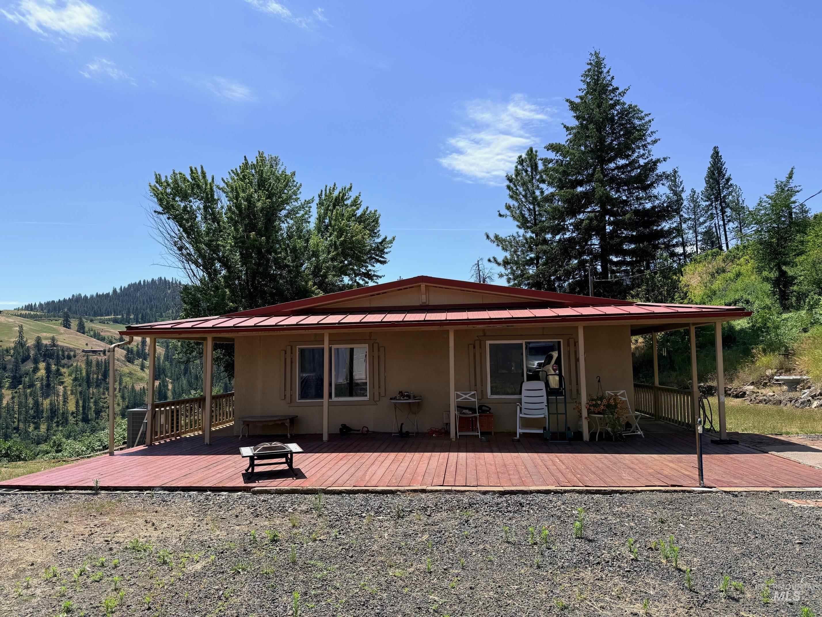 35322 River Road Lenore, ID 83541 - Photo 33 of 42 Single-story residence featuring a terracotta-hued metal roof and an expansive covered front deck with red-stained wood-finish flooring
