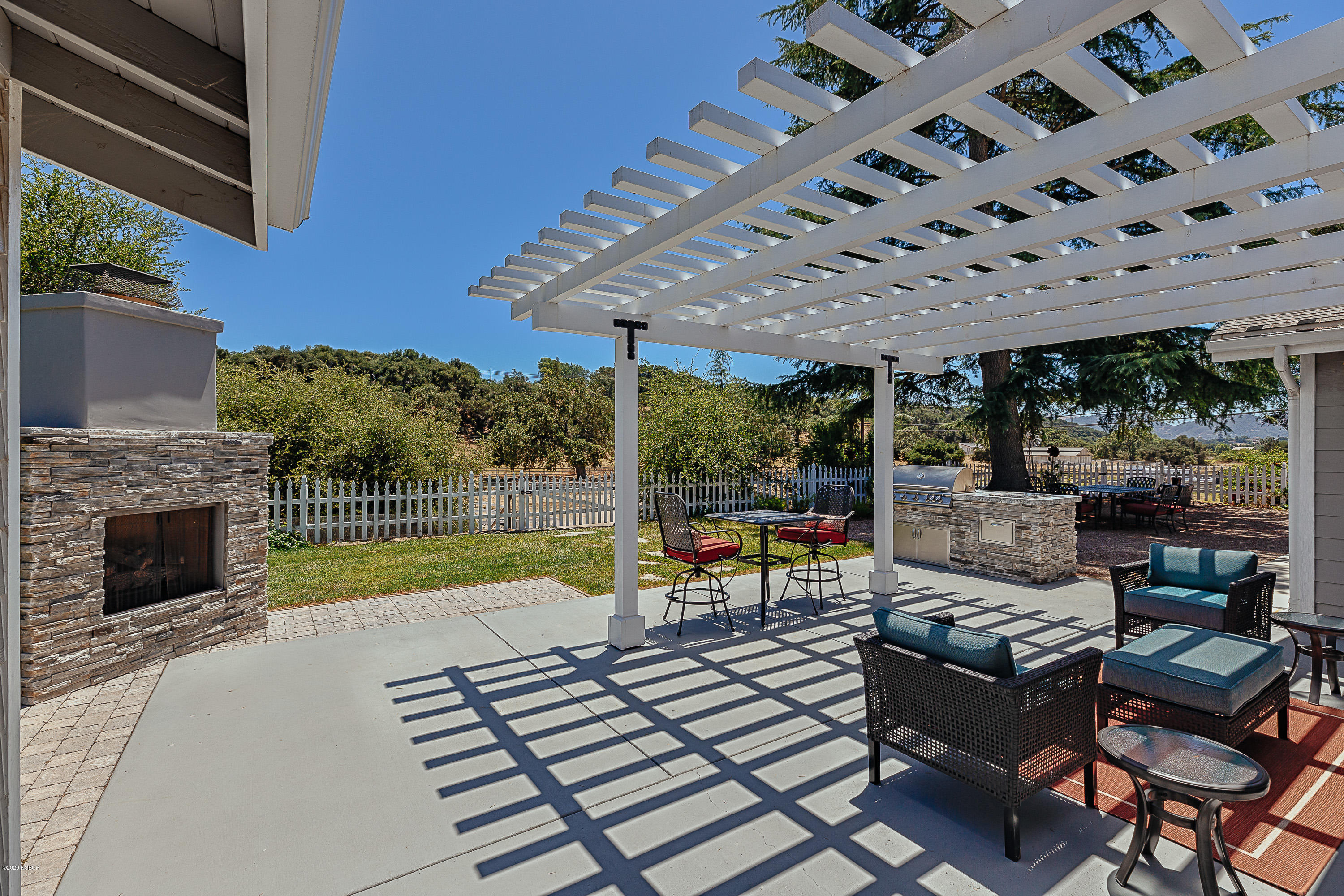 2550 Elk Grove Road Solvang, CA 93463 - Photo 18 of 28 a view of a patio with couches table and chairs under an umbrella with a fireplace