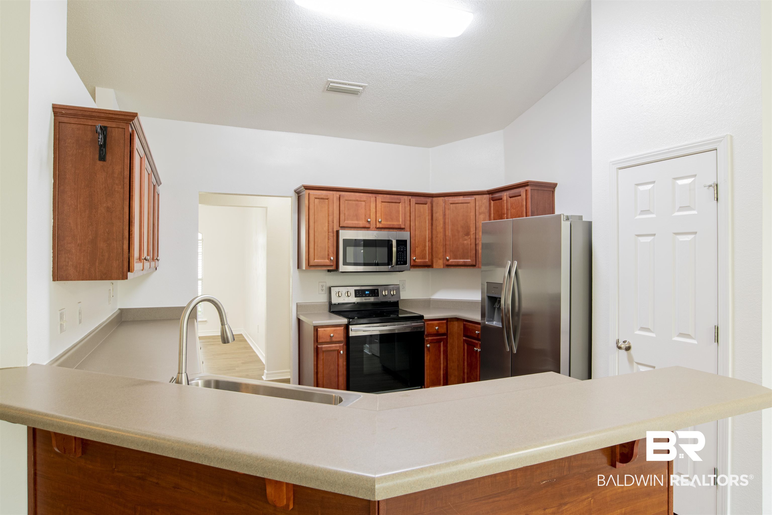 165 Pemberton Loop Fairhope, AL 36532 - Photo 14 of 25 Kitchen featuring light countertops, a peninsula, appliances with stainless steel finishes, a sink, and a breakfast bar area