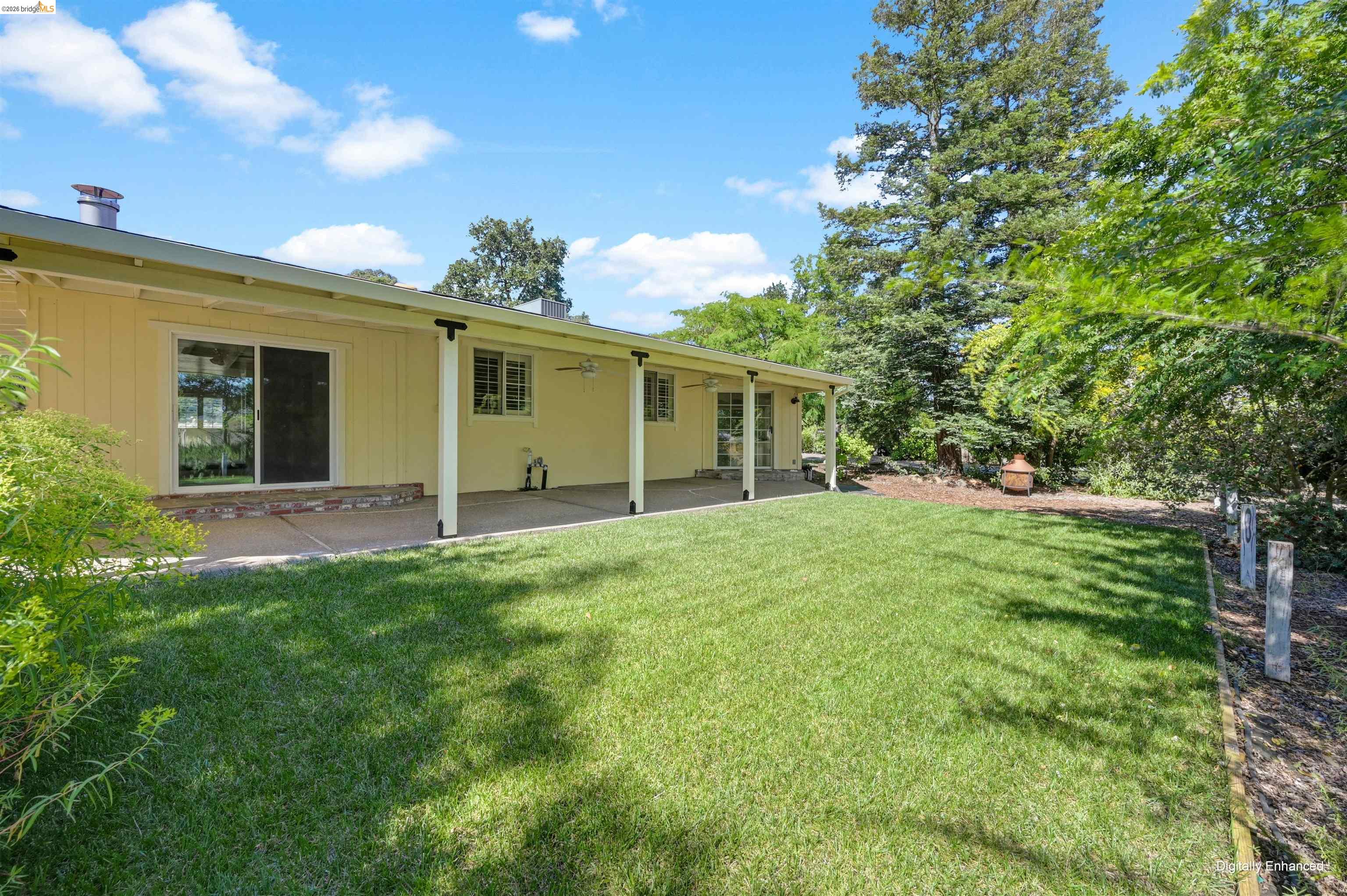 10474 Sheldon Road Elk Grove, CA 95624 - Photo 46 of 83 Expansive backyard featuring a manicured lawn, established perimeter trees, a covered patio with ceiling fans, and sliding glass door access to the interior