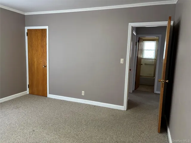 a view of an empty room with closet and a window