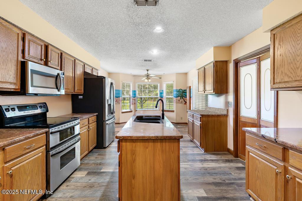 45235 Stratton Road Callahan, FL 32011 - Photo 20 of 44 a kitchen with stainless steel appliances granite countertop a refrigerator a stove top oven a sink dishwasher and wooden cabinets with wooden floor
