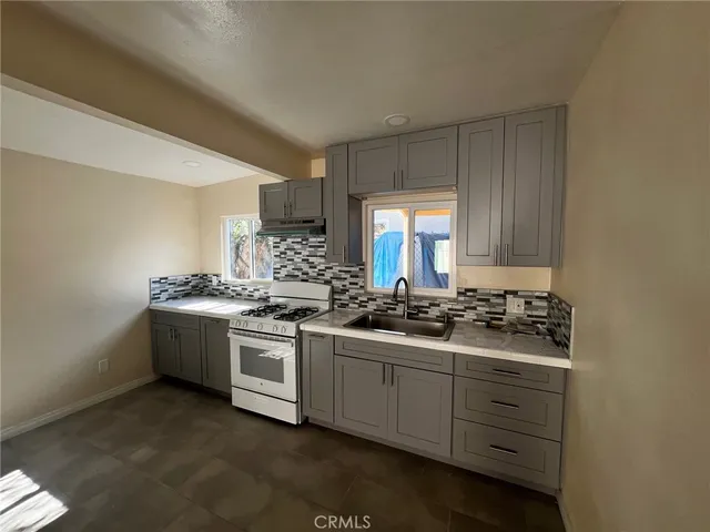 a kitchen with sink a stove and cabinets
