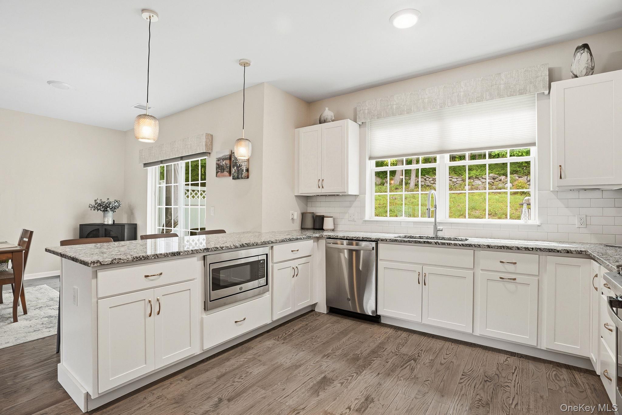 8 Muscoot River Road Granite Springs, NY 10527 - Photo 15 of 40 Modern kitchen featuring white shaker cabinetry, stainless steel appliances, speckled stone countertops, and wood-finish flooring