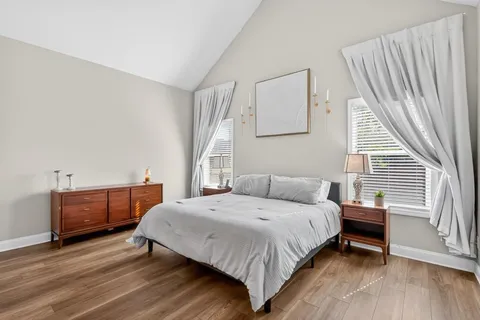 a bedroom with a bed and a large mirror on dresser with wooden floor