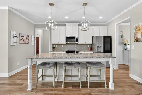 a kitchen with kitchen island granite countertop stainless steel appliances a sink stove and cabinets