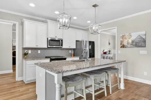 a kitchen with stainless steel appliances granite countertop a refrigerator a stove and a sink with wooden cabinets