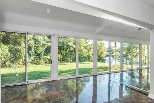 a view of an empty room with wooden floor and a large window