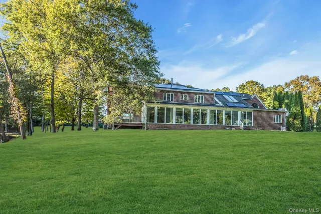 a view of a big house with a big yard and large trees
