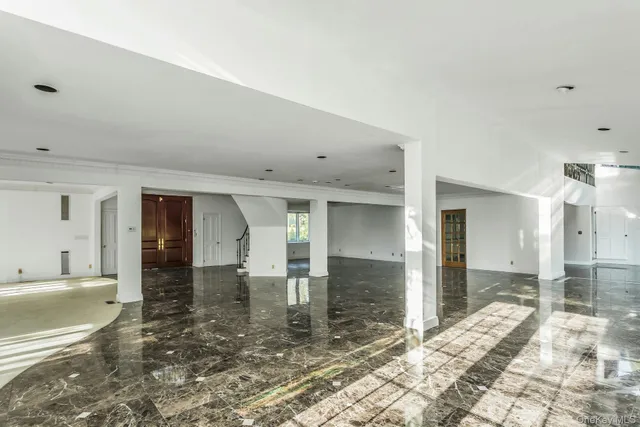 a view of a hallway with wooden floor and a bathroom