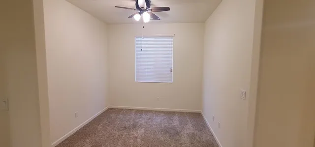 an empty room with a window and a fan