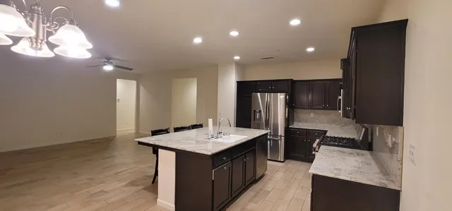 a kitchen with stainless steel appliances granite countertop a sink a stove and a refrigerator