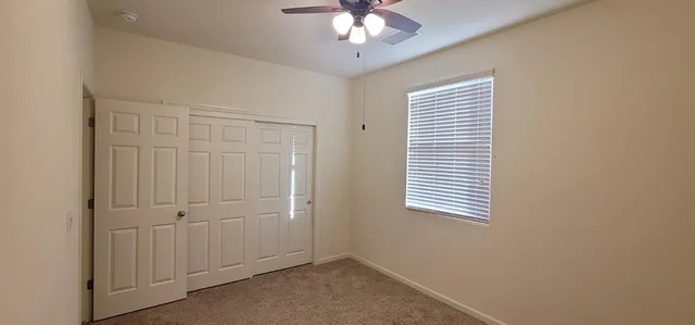 an empty room with windows and fan