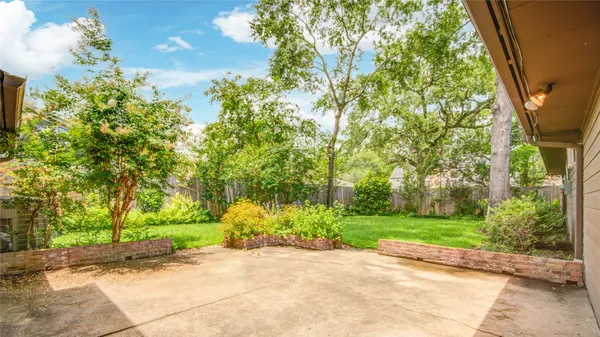 a sidewalk with a building and trees in the background