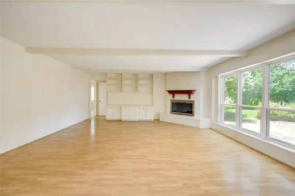 a view of an empty room with a window and a kitchen