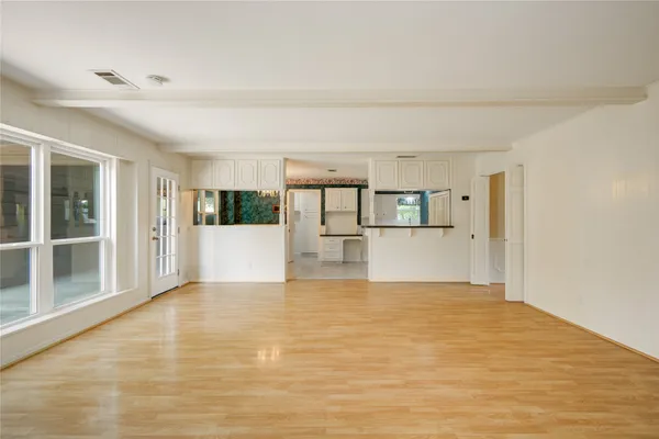 a view of a big room with wooden floor and kitchen