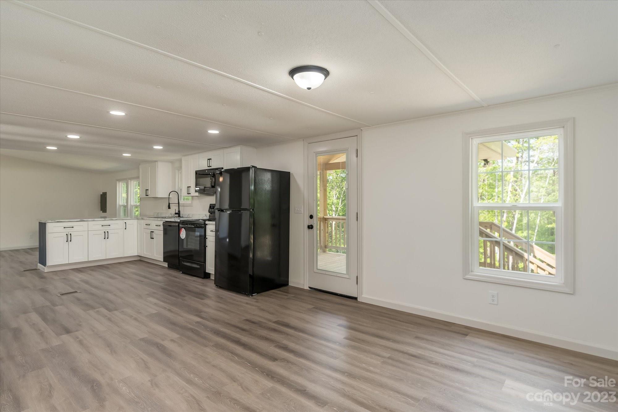 175 King Stepp Road Mill Spring, NC 28756 - Photo 12 of 46 a view of a kitchen with a refrigerator wooden floor and a window