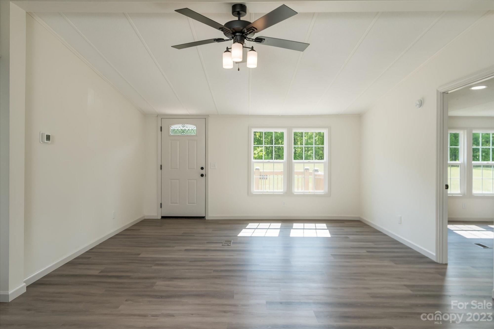 175 King Stepp Road Mill Spring, NC 28756 - Photo 14 of 46 an empty room with wooden floor chandelier fan and windows
