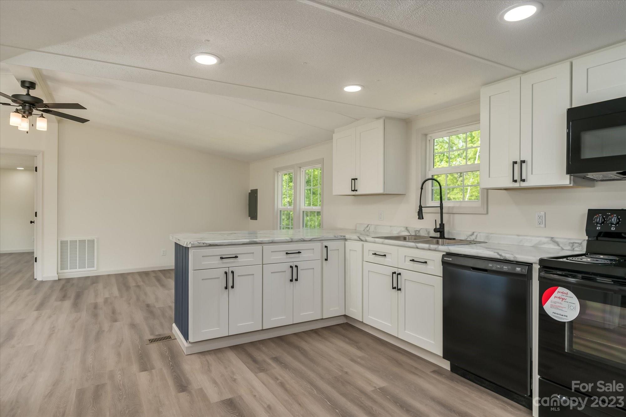 175 King Stepp Road Mill Spring, NC 28756 - Photo 8 of 46 a kitchen with white cabinets stainless steel appliances a sink and a window