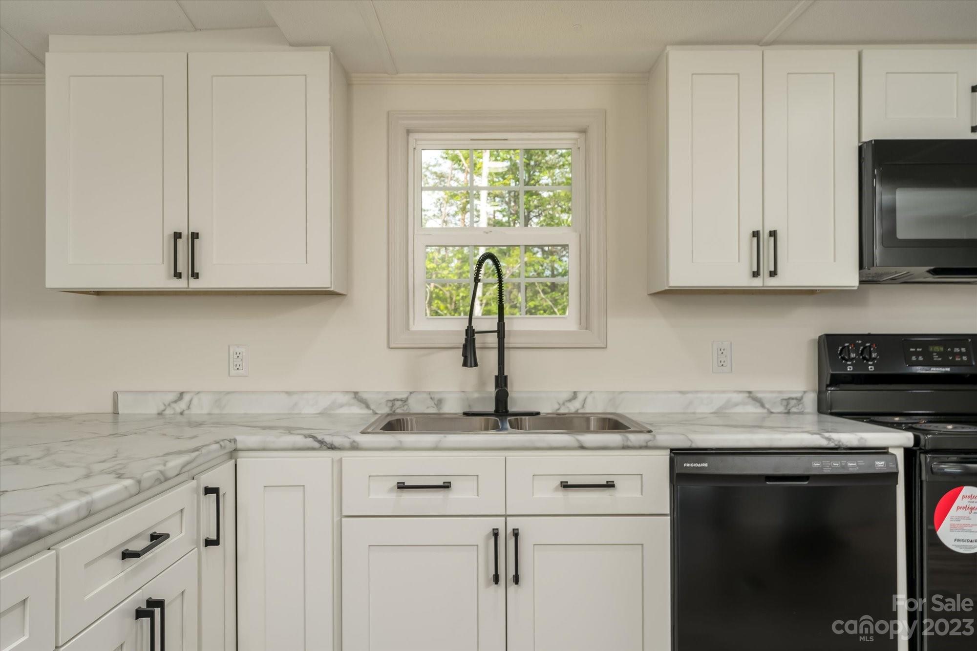 175 King Stepp Road Mill Spring, NC 28756 - Photo 10 of 46 a kitchen with granite countertop white cabinets stainless steel appliances a sink and a window