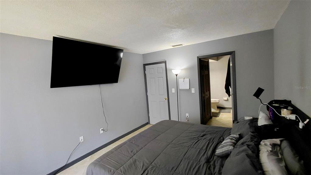 2938 Clark Road, Unit 203 Sarasota, FL 34231 - Photo 12 of 13 a bedroom with a bed and a flat screen tv