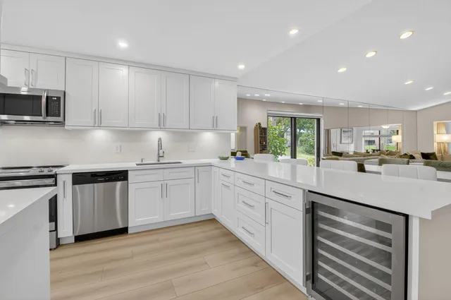 a kitchen with stainless steel appliances a refrigerator a table and chairs