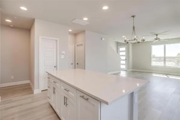 a view of a kitchen island a sink dishwasher a refrigerator and wooden floor