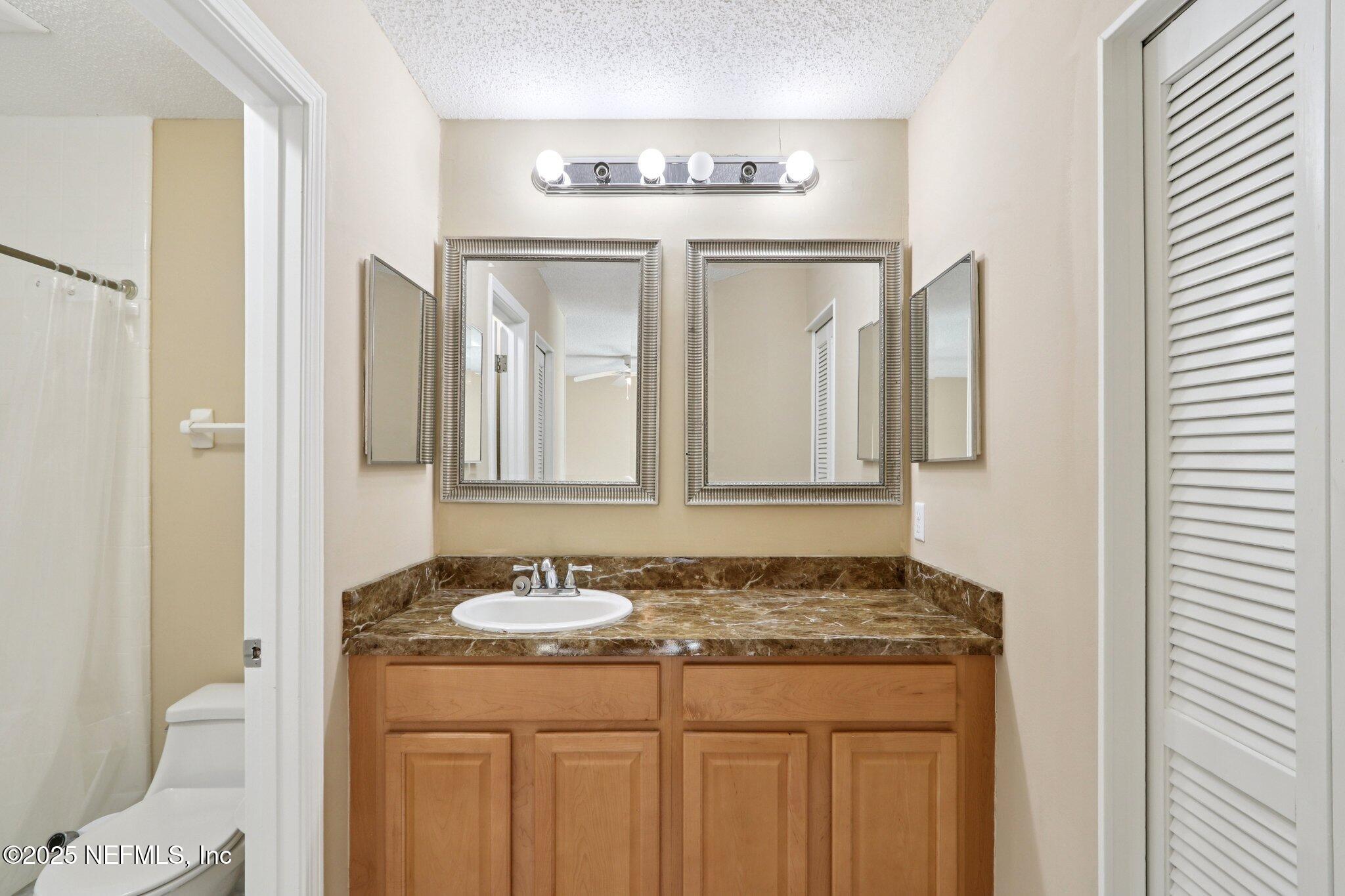 3801 Crown Point Road, Unit 2212 Jacksonville, FL 32257 - Photo 11 of 25 a bathroom with a granite countertop sink and a mirror