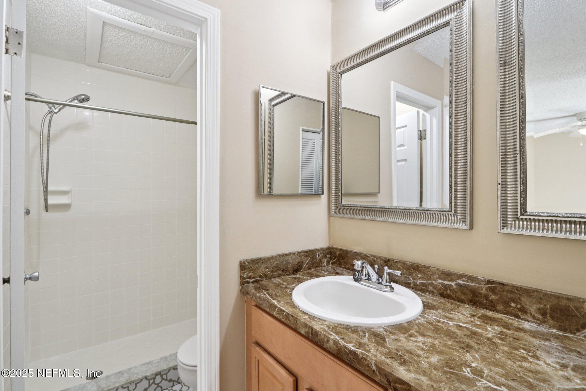 3801 Crown Point Road, Unit 2212 Jacksonville, FL 32257 - Photo 12 of 25 a bathroom with a granite countertop sink and a mirror