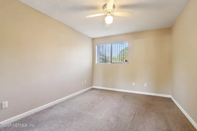 an empty room with windows and fan