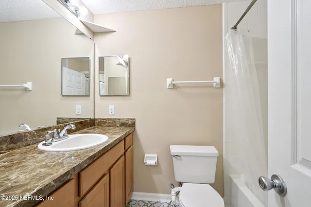 a bathroom with a granite countertop sink toilet and mirror
