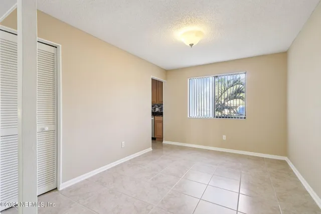 a view of an empty room with window and closet area