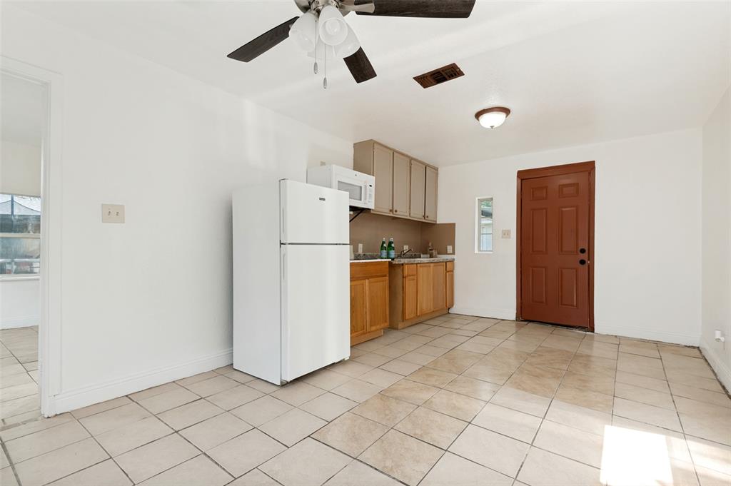 403 North Britain Road, Unit 407B Irving, TX 75061 - Photo 4 of 11 Tile flooring with a compact kitchen featuring wood-finish lower cabinetry, light-colored upper cabinetry, and a ceiling fan